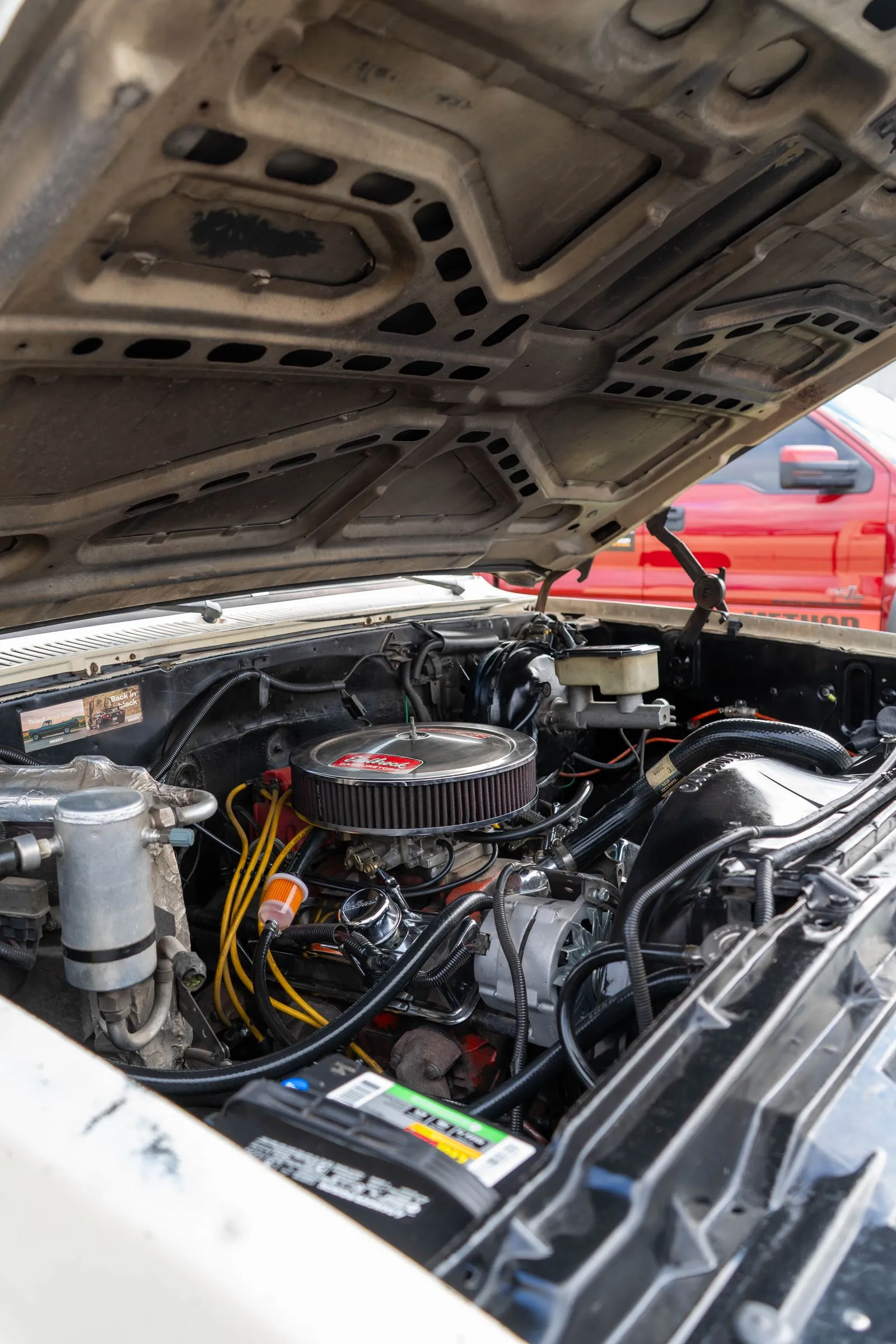 Engine bay of an older pickup with the hood propped open